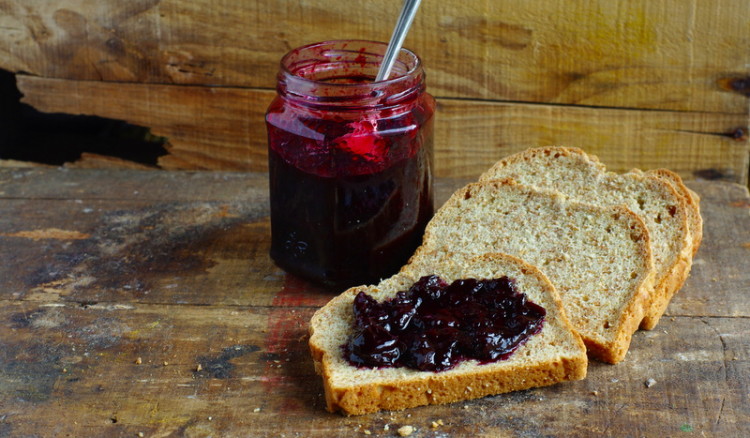 Bread topped with glossy dark burgundy jam.