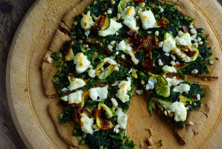 Golden flatbread with dark green pesto and lumps of browned goat's cheese