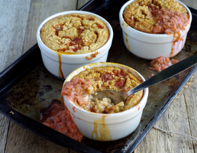 Three small bowls filled with golden baked porridge and oozing with rhubarb.
